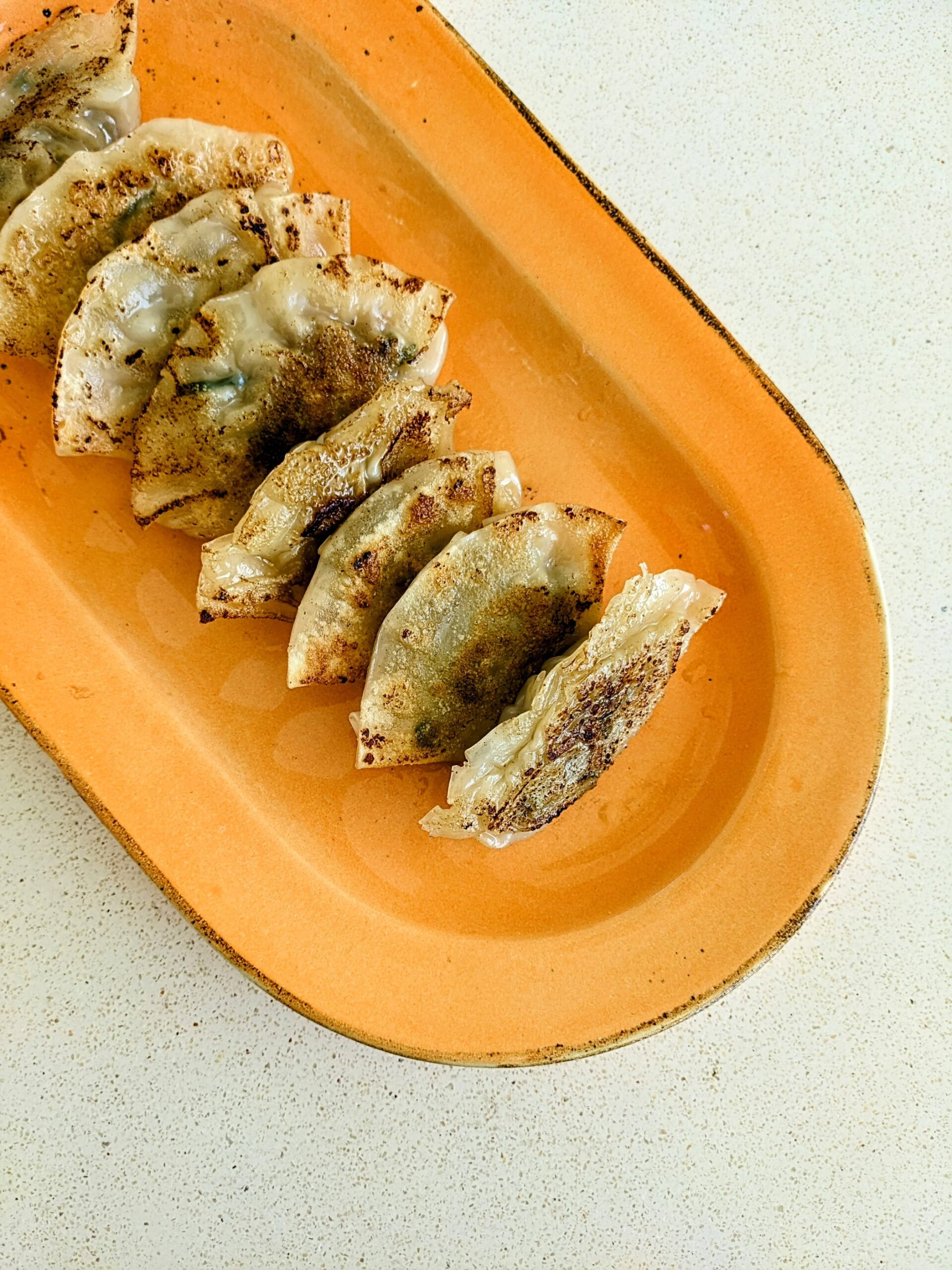 Gyoza disajikan pada piring berwarna oranye