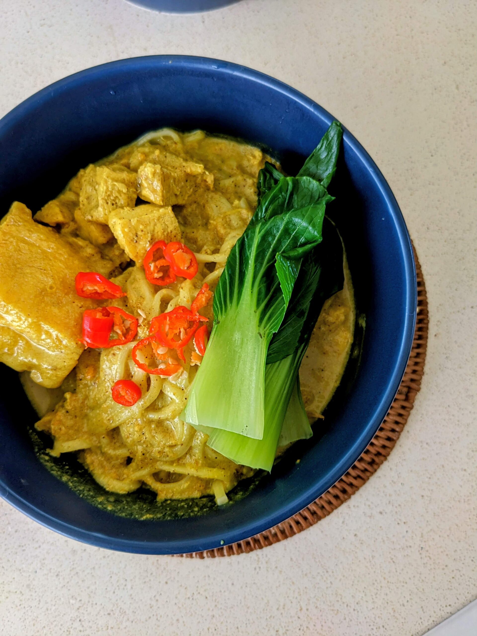 Mie kari ayam disajikan dengan pakcoy dan irisan cabai diatasnya